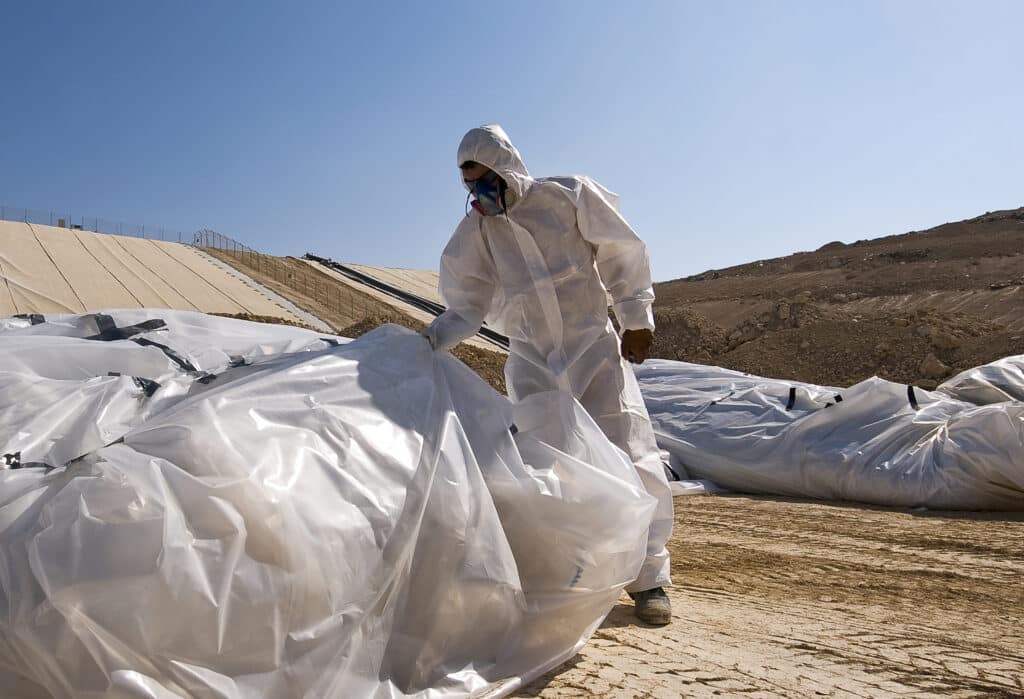 Arbeiter in Schutzanzug bei der Entsorgung von Asbest