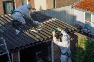 Fachkräfte in Schutzausrüstung bei der Demontage eines Asbestzementdachs
