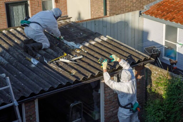 Fachkräfte in Schutzausrüstung bei der Demontage eines Asbestzementdachs