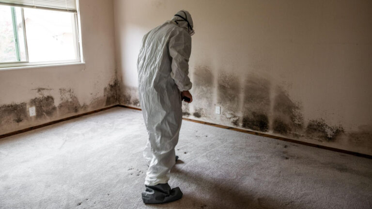 Fachkraft in Schutzanzug und Atemschutz bei Sanierungsarbeiten in einem Innenraum